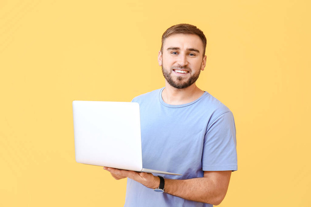 Программист-мужчина с ноутбуком на цветном фоне - Фото, изображение