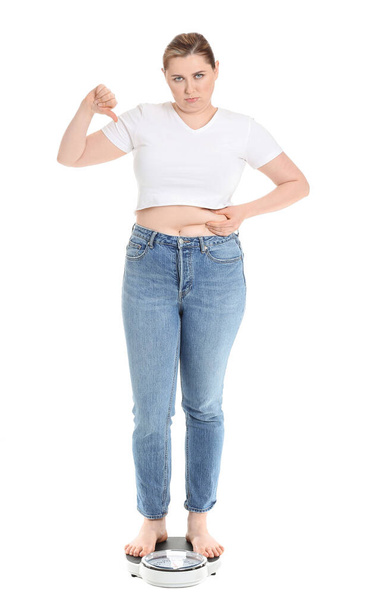 Displeased overweight woman on scales against white background. Weight loss concept - Foto, afbeelding