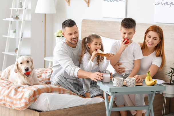 Щаслива сім'я снідає в спальні вдома
 - Фото, зображення