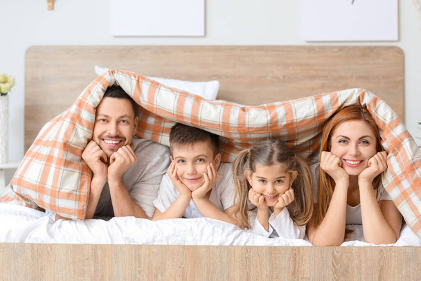 幸せな家族は家でベッドに横たわっている - 写真・画像