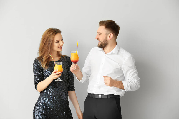 Šťastný pár s koktejly na šedém pozadí - Fotografie, Obrázek