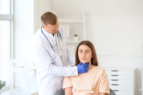 Endocrinólogo examinando garganta de mujer joven en clínica
 - Foto, Imagen