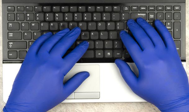 Eller klavyede tıbbi eldivenlerle. Karantina Coronavirus COVID-19 döneminde internetten öğreniyor ya da çalışıyor. Uzak çalışma. - Fotoğraf, Görsel