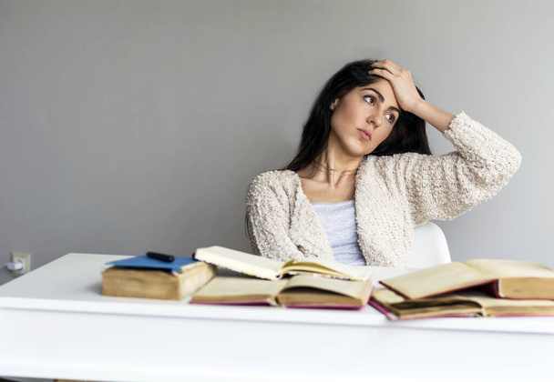 Κουρασμένη φοιτήτρια με πονοκέφαλο μελετώντας για εξετάσεις - Φωτογραφία, εικόνα