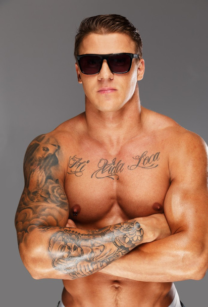 schöner Mann mit Sonnenbrille und muskulös tätowiertem Oberkörper - Foto, Bild