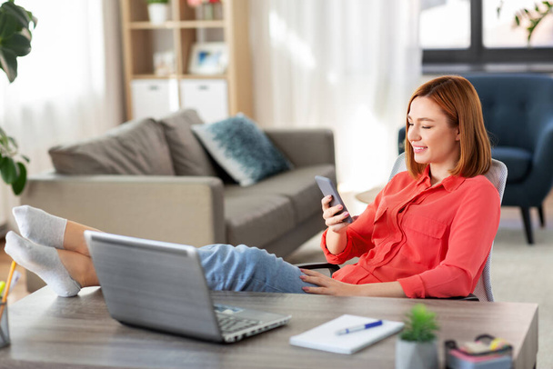 жінка зі смартфоном і ноутбуком в домашньому офісі
 - Фото, зображення