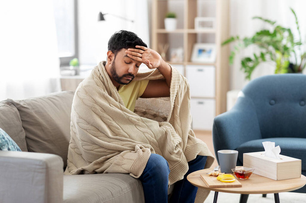 sick young man in blanket having headache or fever - Foto, Bild