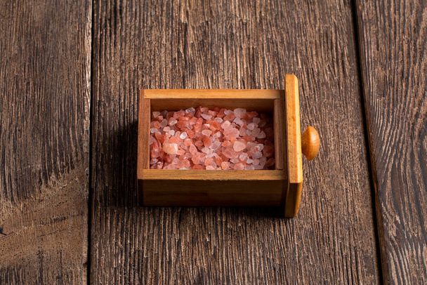 Małe drewniane pudełko wypełnione różową himalajską solą kryształową  - Zdjęcie, obraz