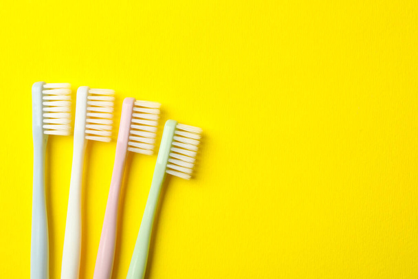 Toothbrushes on yellow background, space for text - Foto, imagen