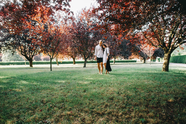 A porttret of a young caucasian stylish couple walking on beautiful park - Foto, Imagen