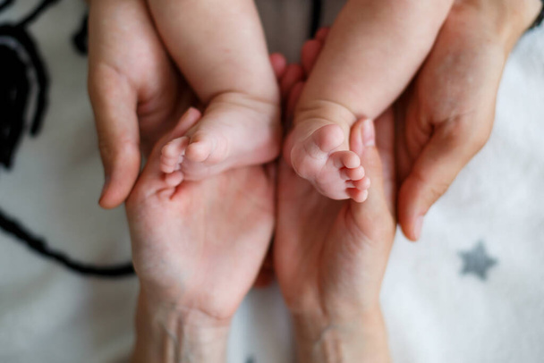 Kinderen benen in de handen van ouders. Foto van baby voeten in de handen van mama en papa - Foto, afbeelding