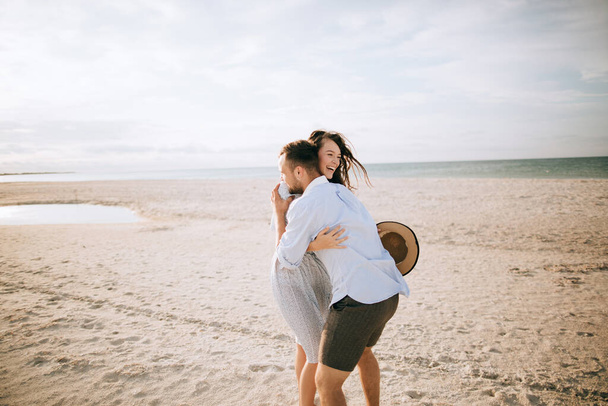 Genç bir çift sahilde yürüyor ve sarılıyorlar. Denizde yaz tatili - Fotoğraf, Görsel