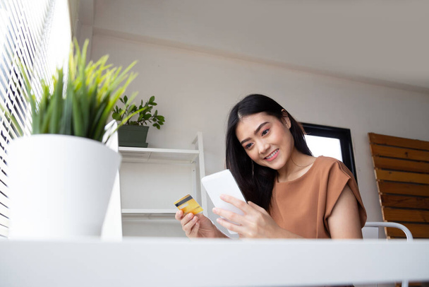 Ázsiai nő használ okostelefon eszközök online vásárlás alkalmazás áruház és fizetés hitelkártyával a nappaliban - Fotó, kép