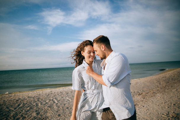 Happy man and woman smiling and hugging at sea beach. Summer holidays and vacations - Фото, изображение
