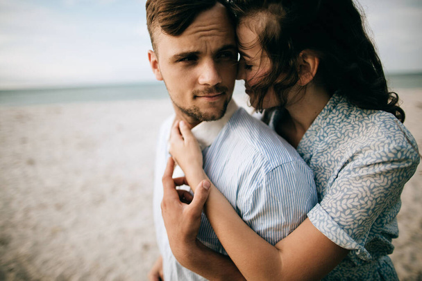 Loving young couple hugging and kissing on the sea beach. Love concept - Фото, изображение
