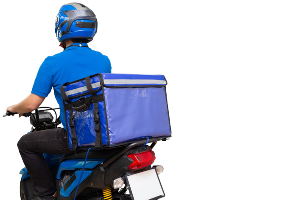 青い制服の乗馬バイクと宅配ボックスを身に着けている配達人。白い背景に隔離された食品や小包エクスプレスサービスを提供するバイク - 写真・画像