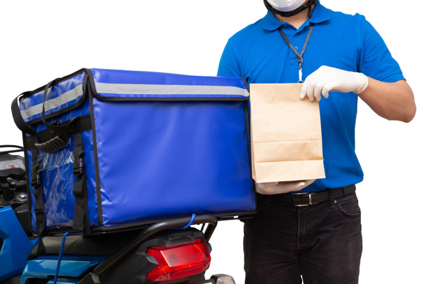 Bezorger in blauw uniform met bezorgdoos. Motorfiets leveren van voedsel of pakket express service geïsoleerd op witte achtergrond - Foto, afbeelding