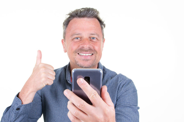 jóképű férfi hüvelykujj fel látszó képernyő telefon okostelefon boldogság mosoly - Fotó, kép