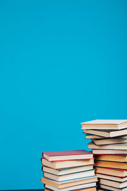 un montón de pilas de libros educativos en la biblioteca de la universidad en un fondo azul
 - Foto, imagen