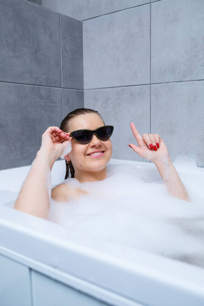 Young woman with sunglasses getting spa treatment in a beauty salon, inside an interior room. Relax in the bathroom without linen. Body care and relaxation concept. - Foto, afbeelding