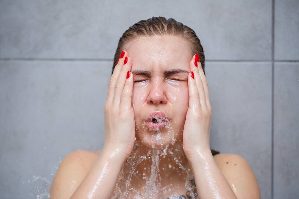Gezichtsverzorging. Vrouw die water met haar handen op het gezicht aanbrengt. Meisje wast haar gezicht met water, wassen op een lichte achtergrond - Foto, afbeelding