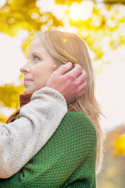 Portrait of handsome man showing affection to his wife in park with lens flare - Foto, Imagem