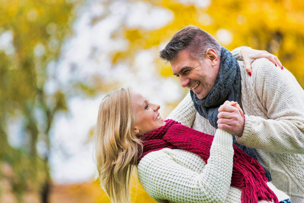 秋を楽しむ熟女夫婦と公園で愛情を示す - 写真・画像