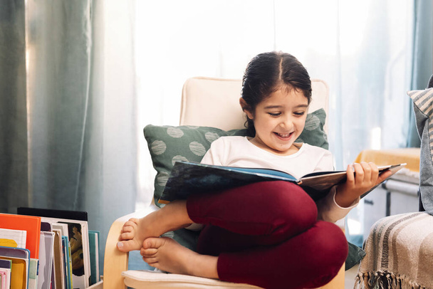 smiling little girl reading sitting at home, concept of leisure at home for children - Valokuva, kuva