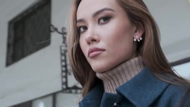 closeup of stylish happy asian pretty girl in blue coat and turtleneck outdoors - Footage, Video