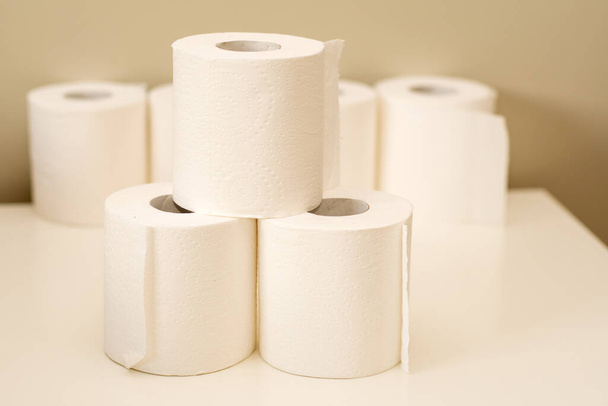 Los rollos de papel higiénico se apilan sobre un fondo neutro. Concepto de escasez y acumulación
 - Foto, Imagen