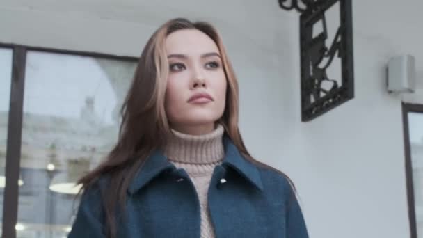 Nahaufnahme von stilvollen glücklich asiatische hübsche Mädchen in blauem Mantel und Rollkragen im Freien - Filmmaterial, Video