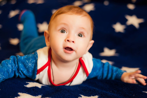 Kleiner Junge liegt auf blauem Hintergrund mit Sternen - Foto, Bild