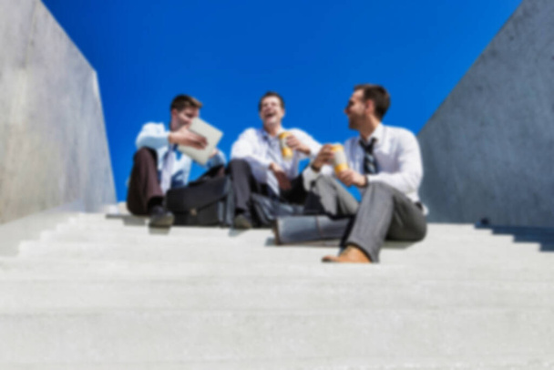 Gruppo di bell'uomo d'affari seduto sulle scale mentre parla durante la pausa
 - Foto, immagini