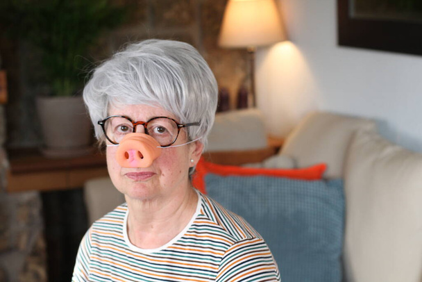 Senior woman wearing pig-style nose - Photo, Image