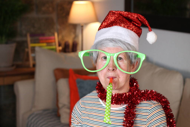 Senior woman using party blower during Christmas - Photo, Image