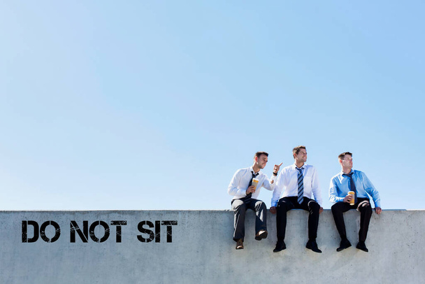 Photo of thoughtful businessmen sitting and relaxing on rooftop during break in office - 写真・画像