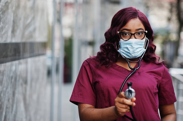 African american female doctor at red lab uniform in protective facial mask. Medicine, profession and healthcare concept. Stop coronavirus infection. - Fotografie, Obrázek