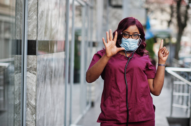 African american female doctor at red lab uniform in protective facial mask. Medicine, profession and healthcare concept. Stop coronavirus infection. - Foto, Bild