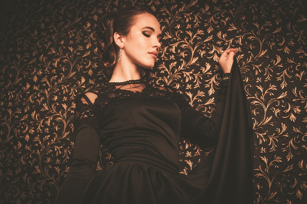 Beautiful young girl wearing black evening dress in luxury interior - Photo, Image
