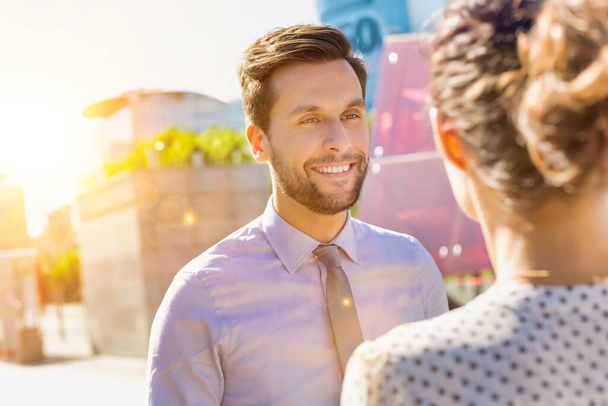 Portrait of young attractive businessman smiling while talking to businesswoman - Fotó, kép