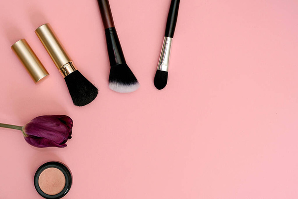 glasses, lipstick, makeup brushes, flower lie on a pink background - Photo, Image