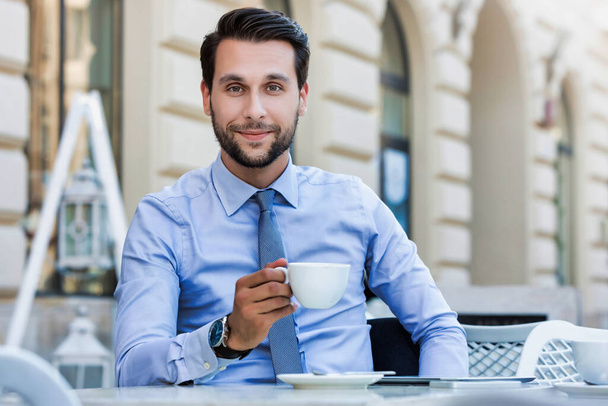 Portrait of young attractive businessman sitting in cafe while drinking coffee - Φωτογραφία, εικόνα