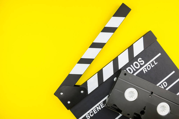 Movie clapper and Video cassette isolated on yellow background. - Photo, Image