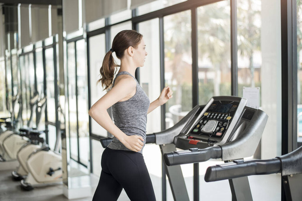 Hübsche junge Sportlerin läuft im Fitnessstudio auf dem Laufband, Gesunder Lebensstil  - Foto, Bild