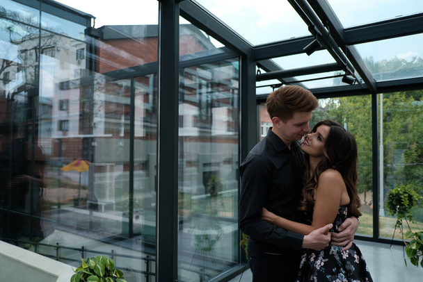 beautiful couple-a girl in a magnificent dress and a guy in a black shirt and trousers are in a building with a beautiful interior - Foto, Imagen