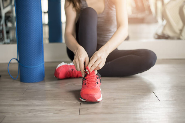 Pretty young sport woman is tying her sneakers in gym, Healthy lifestyle  - Foto, imagen