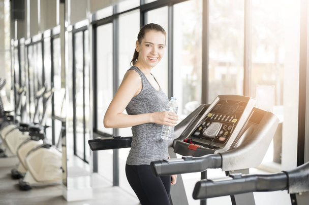Pretty young sport woman is drinking water on treadmill in gym, Healthy lifestyle  - Фото, зображення