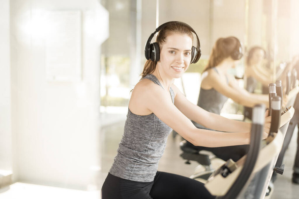 Pretty young sport woman is exercise on bicycle in gym, Healthy lifestyle  - Photo, image