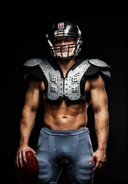American football speler met bal dragen helm en beschermende schilden - Foto, afbeelding