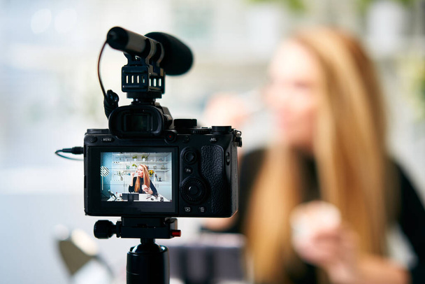 Відображення відео блогу фотоапаратів для блондинки-блогерки з макіяжем в домашній студії. Інфлюенсер Блогер дівчина в прямому ефірі майстер-клас з косметики. Інтернет-навчання та концепція маркетингу
. - Фото, зображення